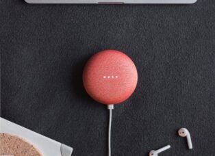 Photography of coral Google Home Mini on black surface beside Apple AirPods
